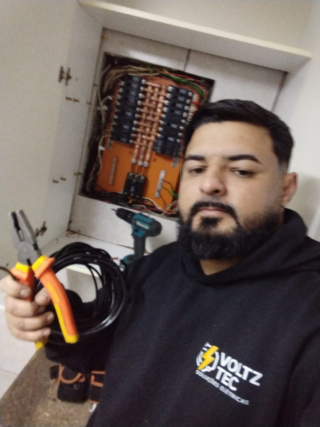 Fundador da VoltzTec com ferramentas em frente a um quadro elétrico