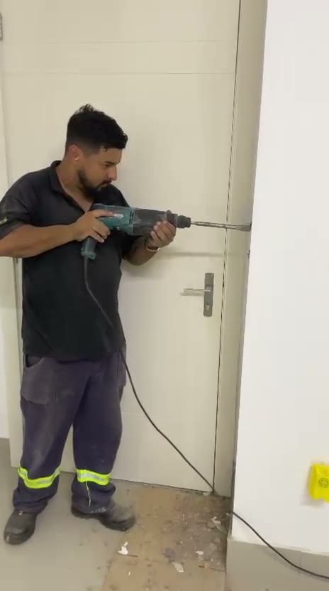 Profissional furando parede durante a obra